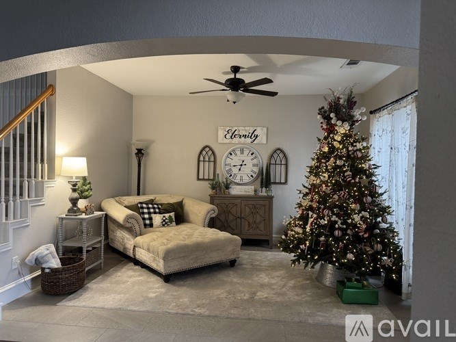 A living room with a Christmas tree and a clock on the wall.