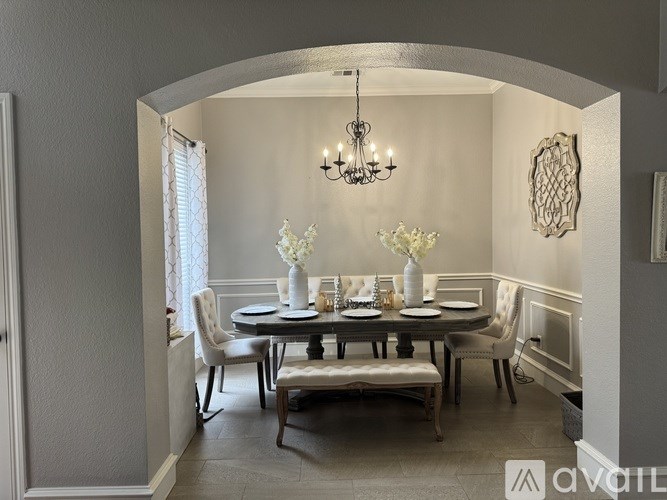 A dining room with a table set for six and a chandelier hanging from the ceiling.