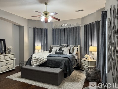A bedroom with a large bed, a ceiling fan, and a mirror on the wall.