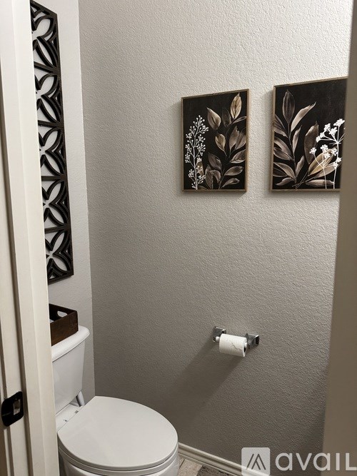 A white toilet in a bathroom with two pictures on the wall.