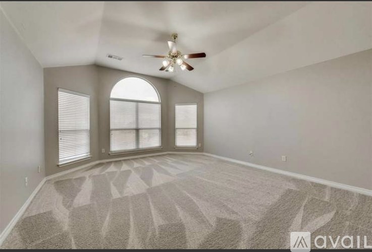 A spacious room with a carpeted floor and a ceiling fan.