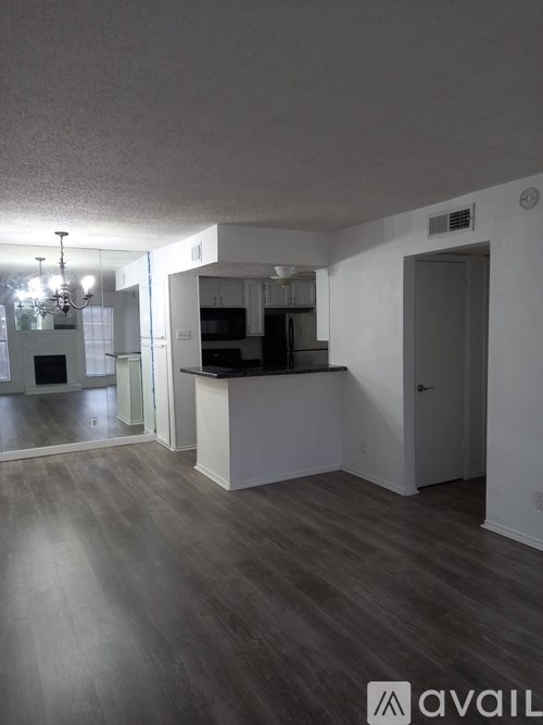 A spacious kitchen and living room with wood flooring and white walls.