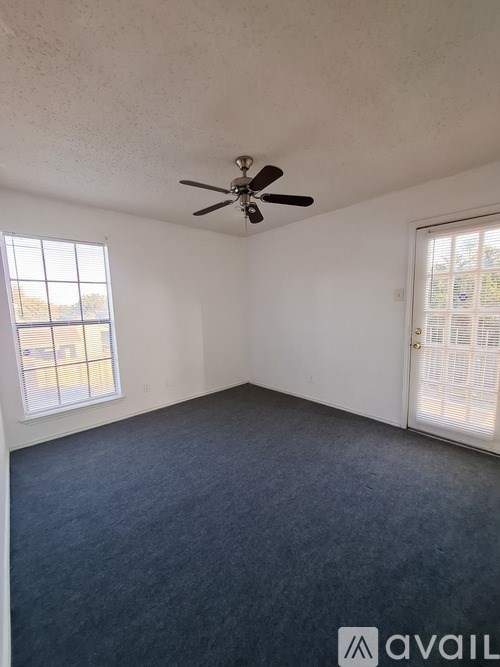 A room with a ceiling fan and two windows.