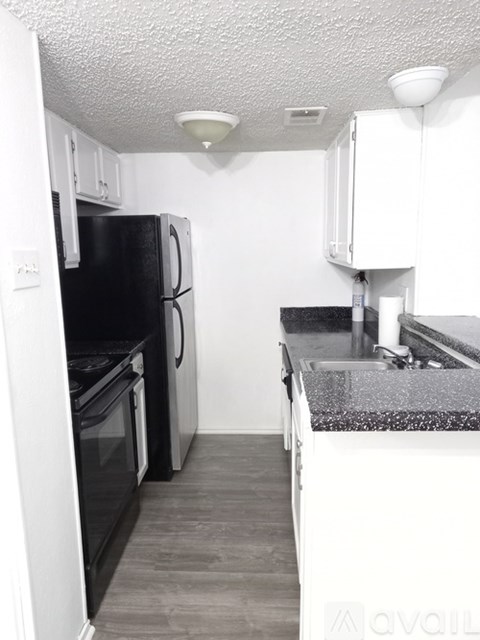 A kitchen with a black fridge and a black stove top oven.