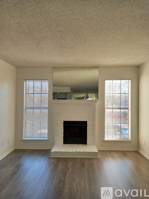 A living room with a fireplace and two windows.