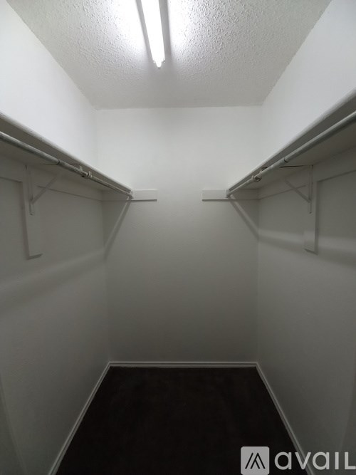 A small, empty walk-in closet with a dark floor and white walls.