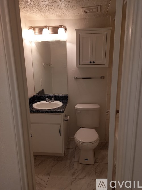 A small bathroom with a toilet, sink and cabinet.