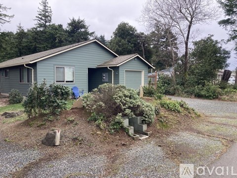 A house with a blue garage door is surrounded by greenery.