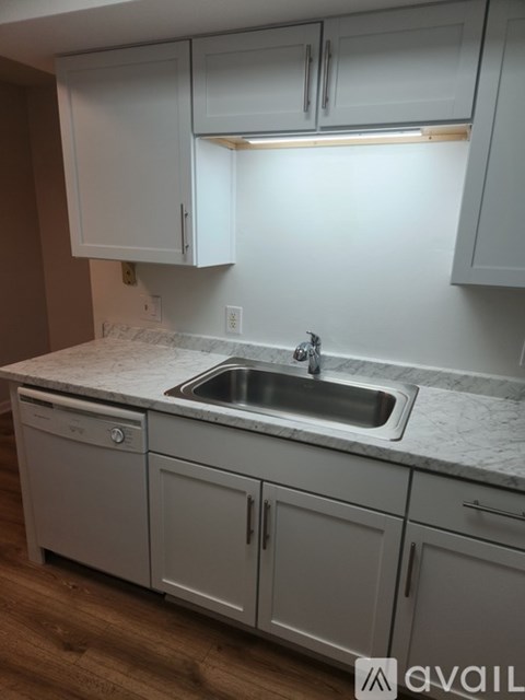 A kitchen with white cabinets and a marble countertop.