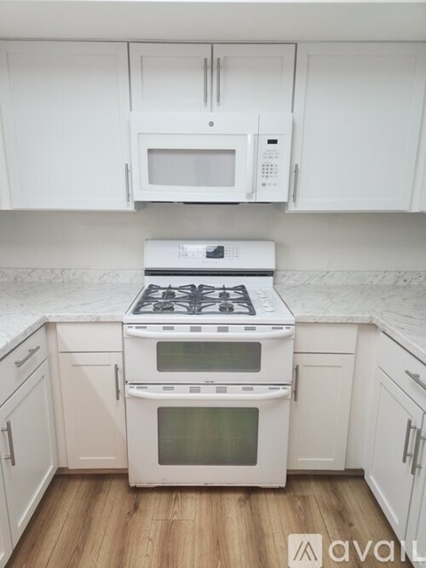 A white kitchen with a stove top oven and microwave above it.
