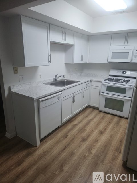 A kitchen with white cabinets and a wooden floor.