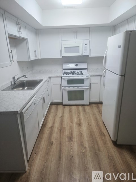 A kitchen with white cabinets and a wooden floor.