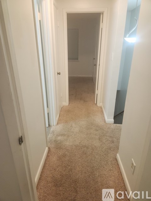 A hallway with carpeted floors and white walls.