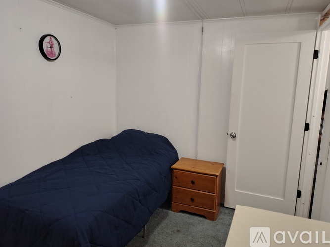 A bedroom with a bed, chair, and wooden table.