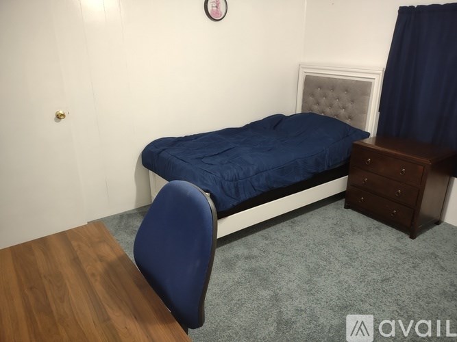 A bedroom with a bed, chair, and wooden table.