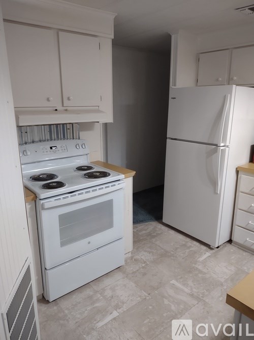 A white kitchen with a stove and refrigerator.