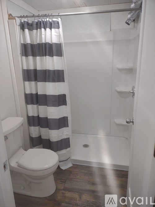 A bathroom with a toilet, a shower curtain, and a towel rack.