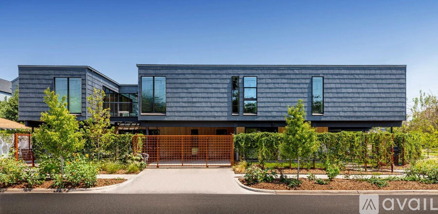 A modern house with a black exterior and a large front yard.