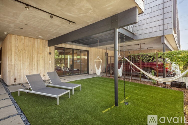 A modern outdoor lounge area with two lounge chairs and a hammock.