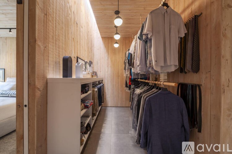 A clothing store with clothes hanging on racks and shelves with a white sofa in the background.