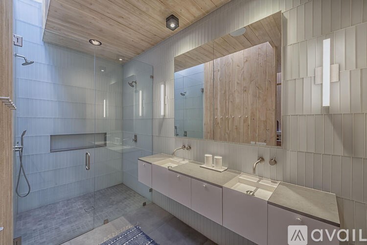 A modern bathroom with a wooden ceiling and a glass shower area.