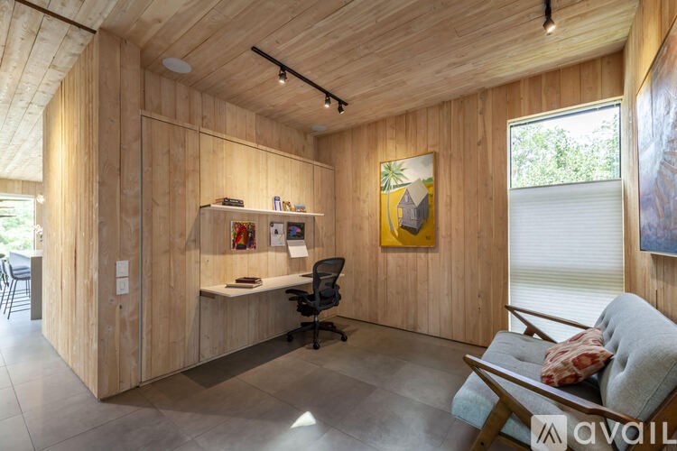 A room with wooden walls and a desk with a chair.