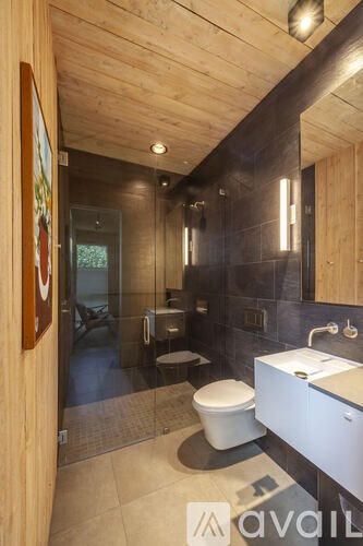 A bathroom with a toilet, sink, and mirror.