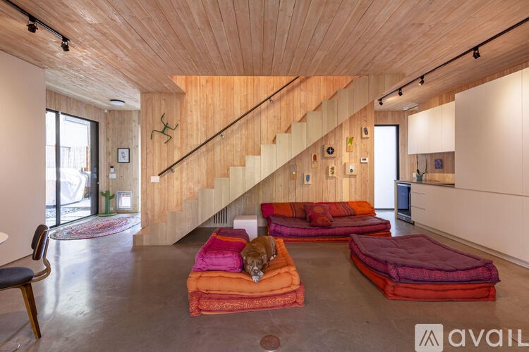 A wooden staircase leads up to a white wall with a cabinet underneath.