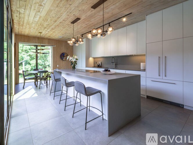 A modern kitchen with a wooden ceiling and a long island with chairs.