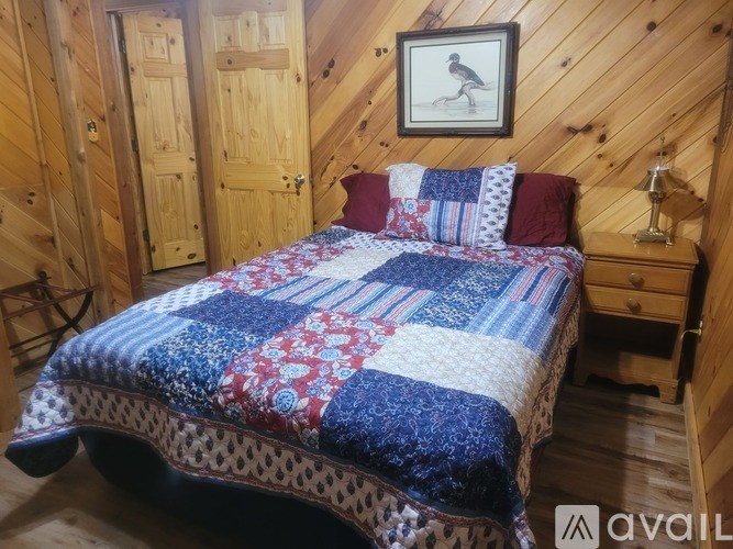 A bed with a quilt and pillows in a room with wooden walls.