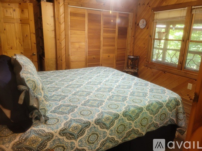 A bedroom with a bed covered in a blue and green patterned bedspread.