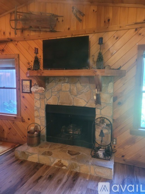 A stone fireplace with a TV above it in a wooden room.
