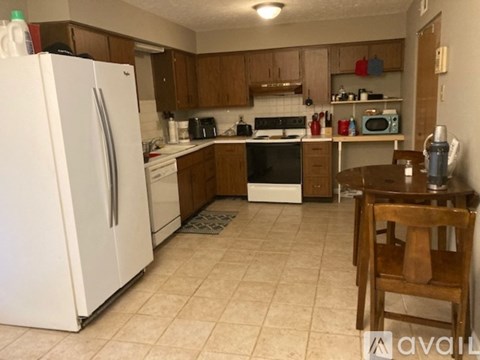 A kitchen with a white fridge and wooden chairs.