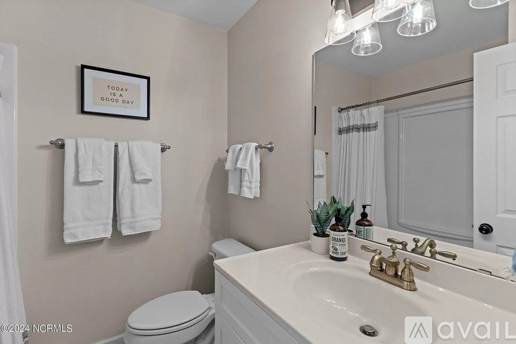 A bathroom with a toilet, sink, mirror, and towel rack.