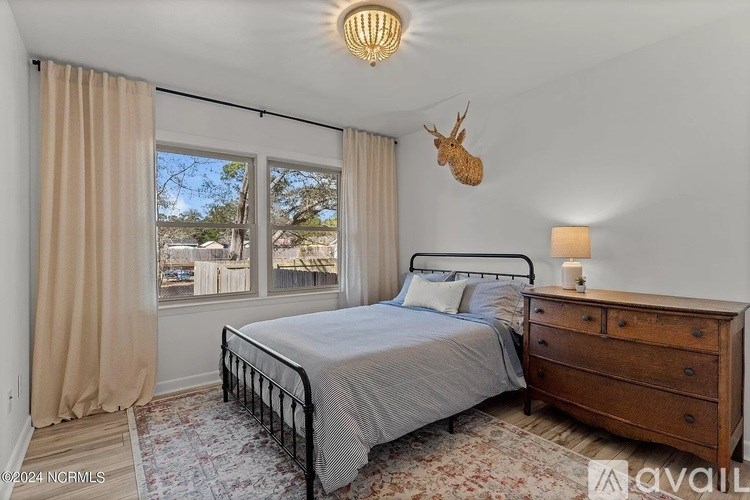A bedroom with a bed, nightstand, and a deer head on the wall.