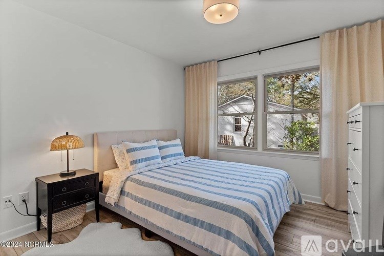 A bedroom with a bed, nightstand, and window.