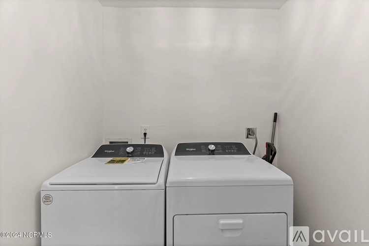 Two white front loading washing machines in a laundry room.