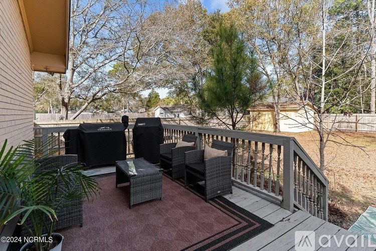 A patio with a table and chairs overlooking a yard.