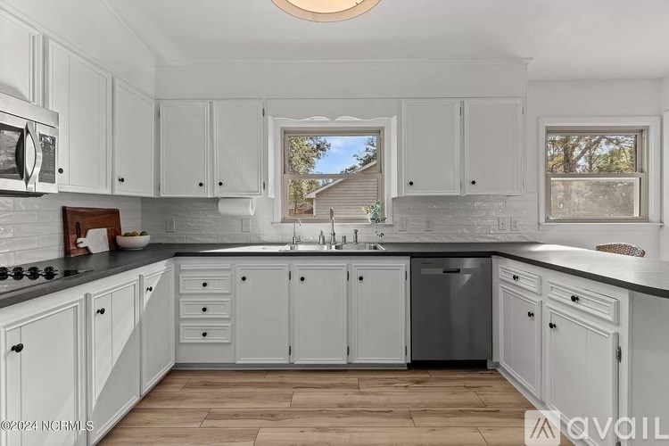 A kitchen with white cabinets and a wooden countertop.