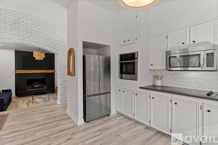 A kitchen with white cabinets and a brick fireplace.