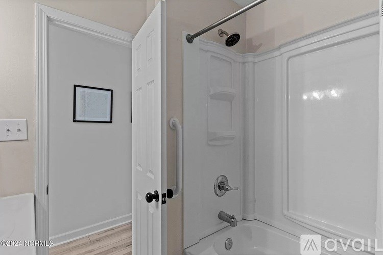 A white bathroom with a door and a picture on the wall.