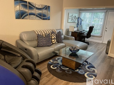 A living room with a grey couch and a glass coffee table.