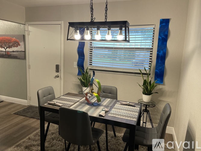 A dining room with a table set for four and a chandelier hanging from the ceiling.