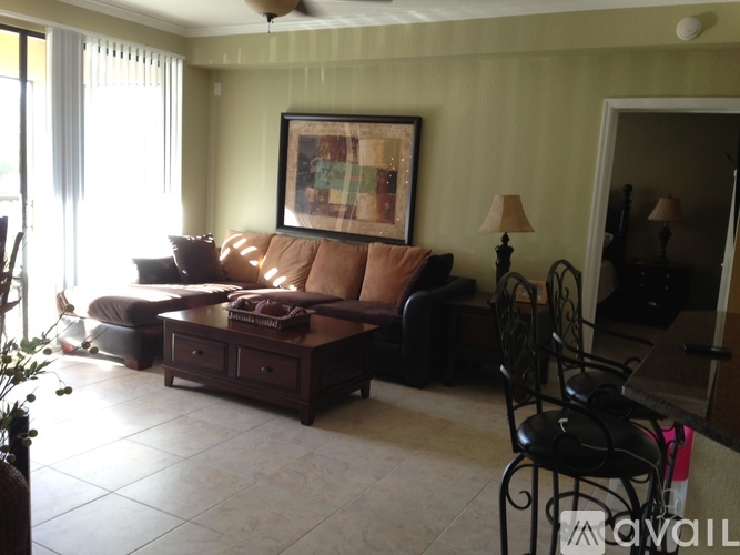 A living room with a brown couch and a painting on the wall.