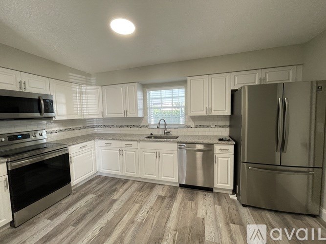 A kitchen with white cabinets and a stainless steel refrigerator.