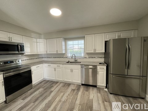 A kitchen with white cabinets and a stainless steel refrigerator.