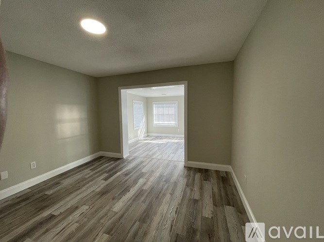 A room with wooden flooring and a doorway leading to another room.