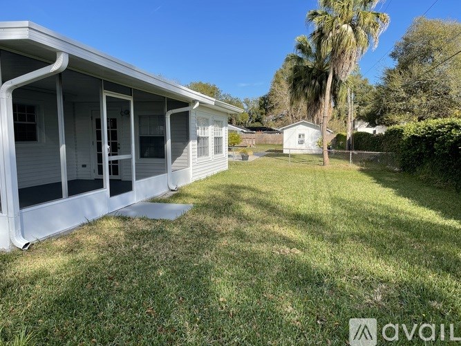 A house with a white exterior and a porch is surrounded by a grassy area.