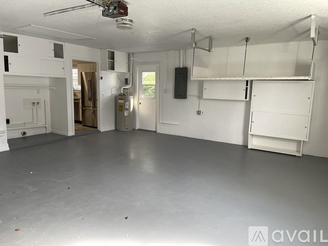 A spacious garage with a ceiling fan and white cabinets.
