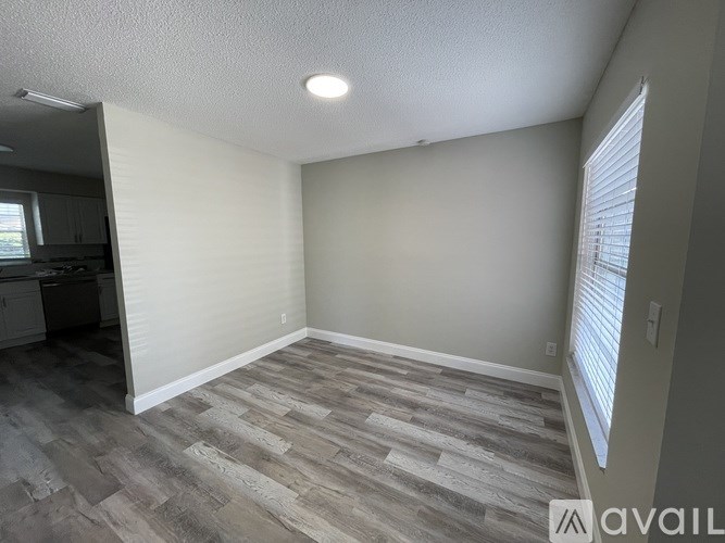 A room with wooden flooring and a window with blinds.